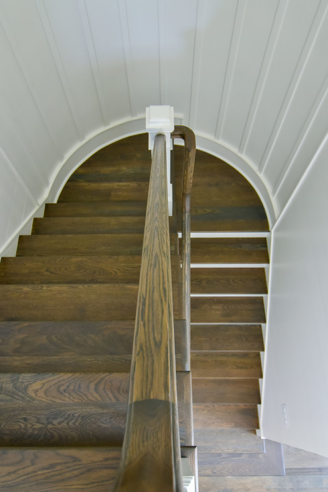 Large traditional wood curved staircase in Charleston with painted wood risers and mixed railing.