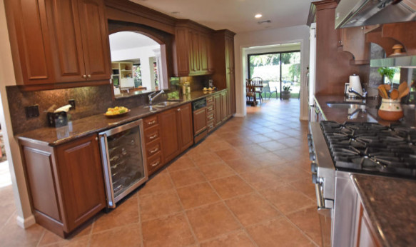 Example of a large transitional galley terra-cotta tile enclosed kitchen design with an undermount sink, beaded inset cabinets, medium tone wood cabinets, granite countertops, brown backsplash, stainless steel appliances, porcelain backsplash and brown countertops