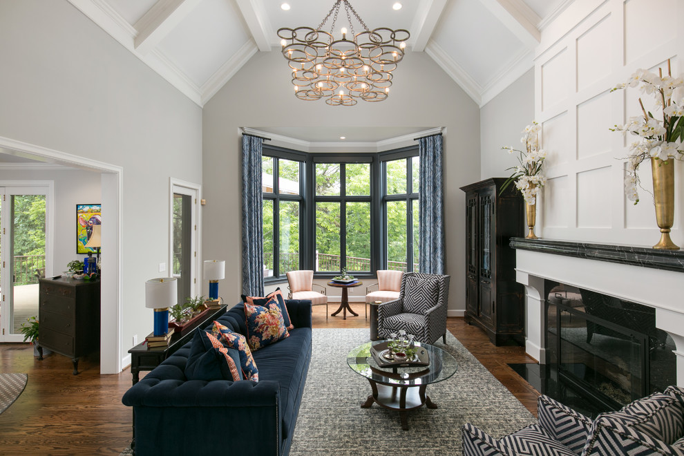 Photo of a large traditional formal living room in Kansas City with grey walls, medium hardwood floors, a standard fireplace, a stone fireplace surround, no tv and brown floor.