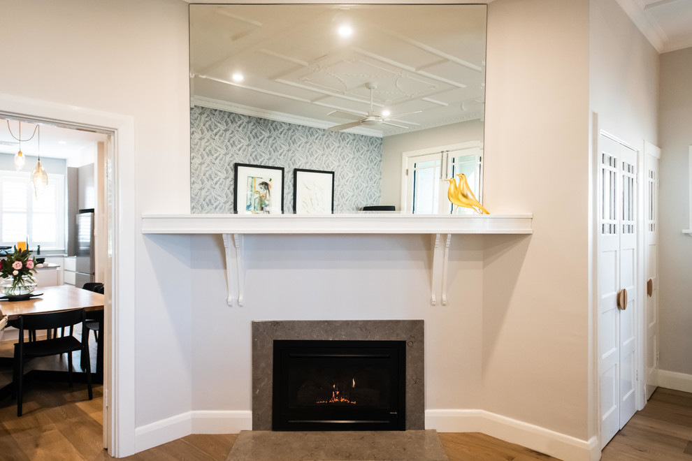 This is an example of a mid-sized contemporary open plan dining in Melbourne with grey walls, medium hardwood floors, a standard fireplace, a stone fireplace surround and brown floor.