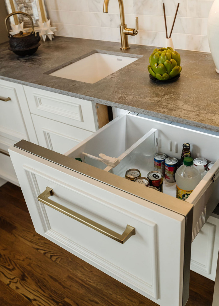 Example of a beach style medium tone wood floor kitchen design with white cabinets and an island