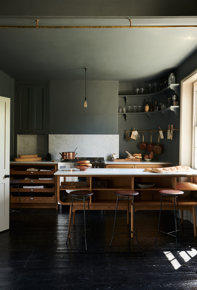 Inspiration for a mid-sized midcentury eat-in kitchen in London with a farmhouse sink, medium wood cabinets, marble benchtops, white splashback, marble splashback, stainless steel appliances, painted wood floors, with island, black floor and white benchtop.