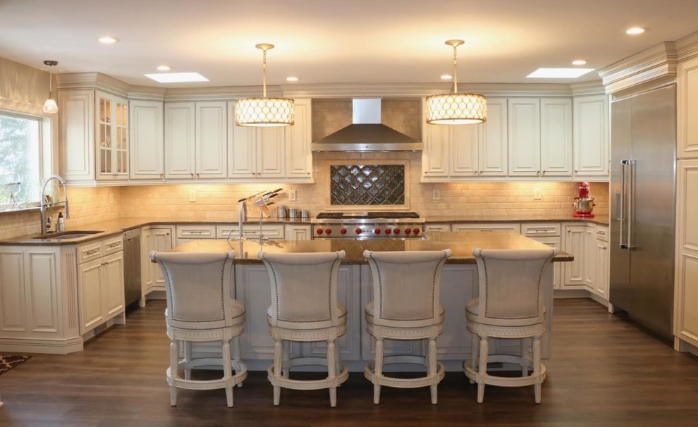 Large transitional u-shaped eat-in kitchen in New York with an undermount sink, raised-panel cabinets, white cabinets, quartzite benchtops, beige splashback, terra-cotta splashback, stainless steel appliances, with island, medium hardwood floors, brown floor and brown benchtop.