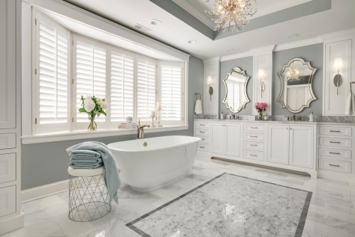 Luxury bathroom cabinets in white with marble countertop, elegant mirrors, chandelier lighting, and freestanding bathtub in a modern spa-like bathroom