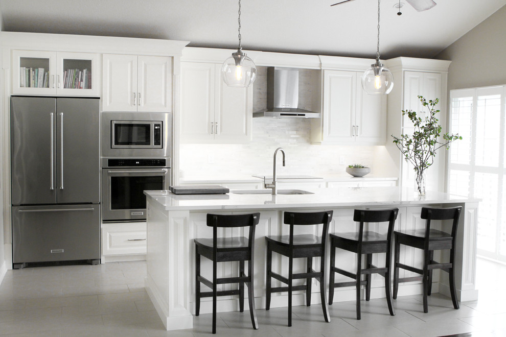 Inspiration for a mid-sized transitional single-wall eat-in kitchen remodel in Toronto with an undermount sink, raised-panel cabinets, white cabinets, marble countertops, white backsplash, stainless steel appliances and an island