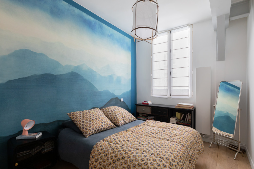 This is an example of a mid-sized traditional master bedroom in Paris with blue walls, light hardwood floors, no fireplace, beige floor and wallpaper.