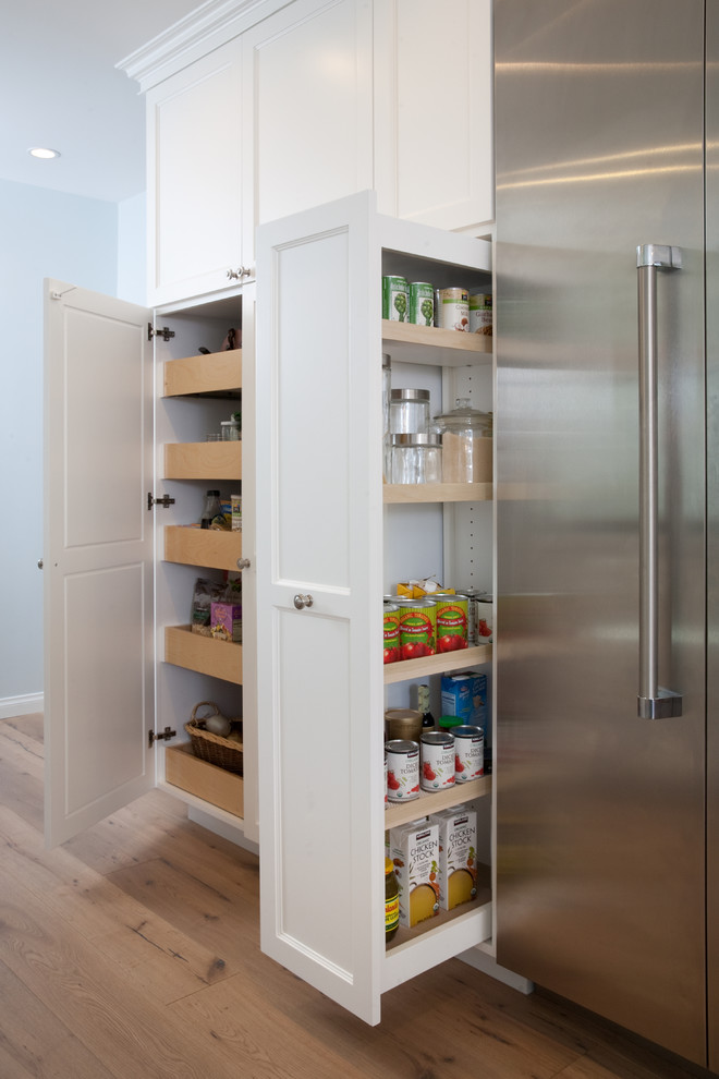 Eat-in kitchen - large coastal l-shaped medium tone wood floor eat-in kitchen idea in Los Angeles with a farmhouse sink, shaker cabinets, white cabinets, blue backsplash, mosaic tile backsplash, stainless steel appliances, an island and marble countertops