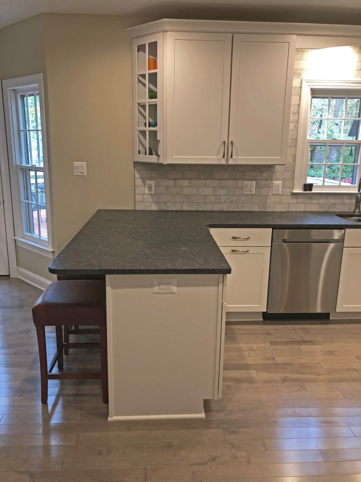 Inspiration for a small transitional u-shaped eat-in kitchen in Baltimore with a double-bowl sink, shaker cabinets, white cabinets, granite benchtops, grey splashback, marble splashback, stainless steel appliances, light hardwood floors, a peninsula, beige floor and grey benchtop.