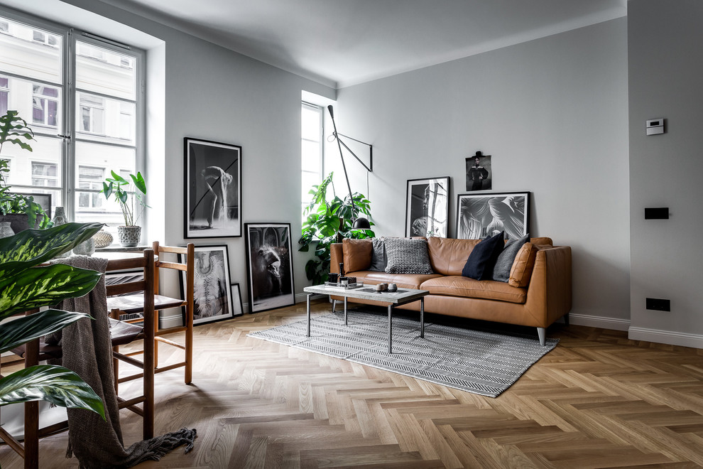 This is an example of a mid-sized scandinavian formal open concept living room in Stockholm with grey walls, light hardwood floors, no fireplace and no tv.
