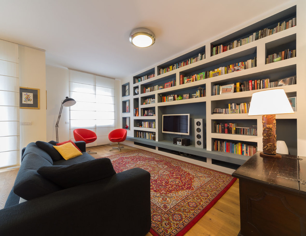 Large eclectic open concept living room in Milan with a library, white walls, medium hardwood floors, a wall-mounted tv and brown floor.