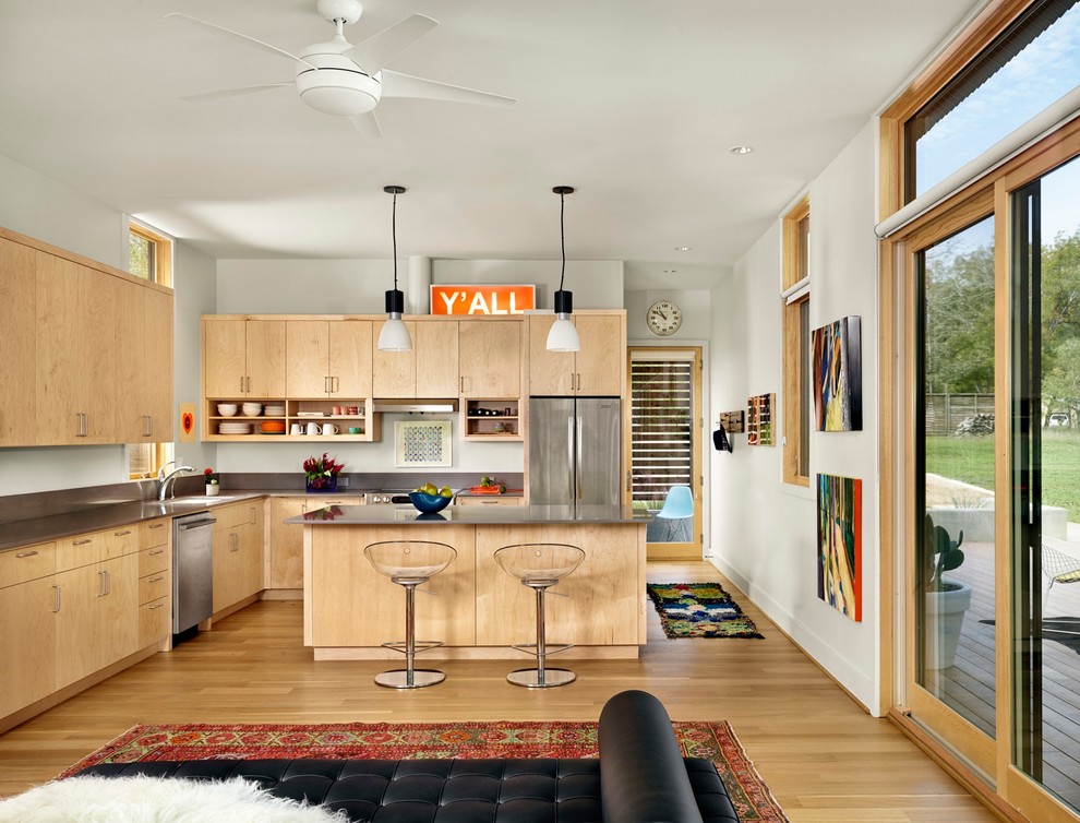 Inspiration for a contemporary l-shaped open plan kitchen in Austin with an undermount sink, flat-panel cabinets, light wood cabinets, stainless steel appliances, light hardwood floors and with island.