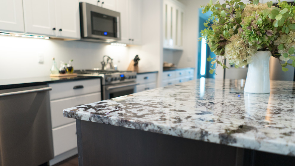 Example of a mid-sized transitional l-shaped dark wood floor open concept kitchen design with an undermount sink, shaker cabinets, white cabinets, granite countertops, gray backsplash, stainless steel appliances and an island