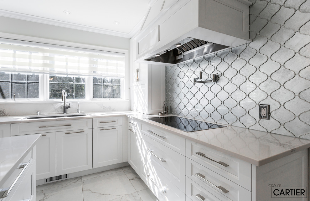 Example of a huge transitional l-shaped marble floor eat-in kitchen design in Montreal with an undermount sink, shaker cabinets, white cabinets, quartzite countertops, gray backsplash, glass tile backsplash, paneled appliances and an island