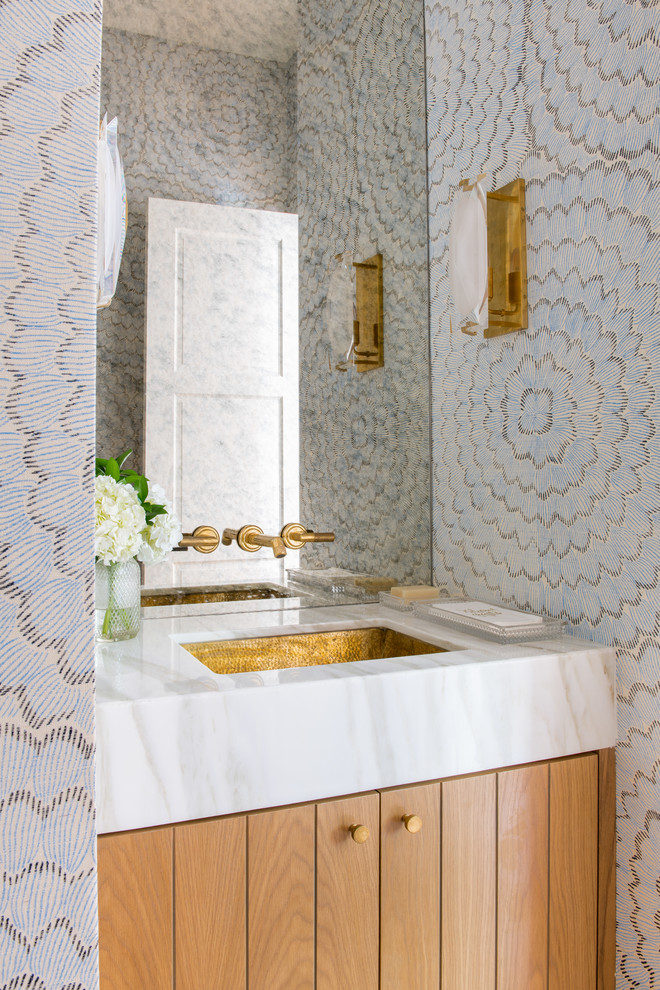 Example of a beach style powder room design in Dallas with medium tone wood cabinets, multicolored walls, an undermount sink and white countertops