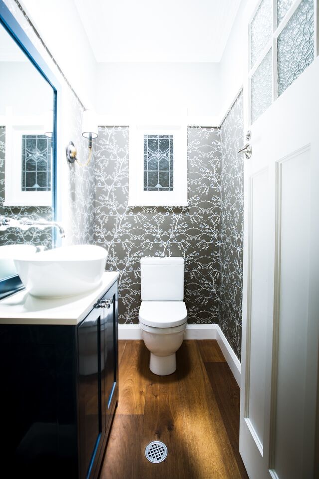 Small traditional powder room in Sydney with shaker cabinets, blue cabinets, a one-piece toilet, brown walls, medium hardwood floors, a vessel sink, engineered quartz benchtops, brown floor and white benchtops.