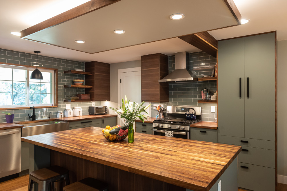 Photo of a mid-sized transitional u-shaped eat-in kitchen in Denver with a farmhouse sink, flat-panel cabinets, green cabinets, wood benchtops, green splashback, glass tile splashback, coloured appliances, medium hardwood floors, with island, brown floor, brown benchtop and exposed beam.