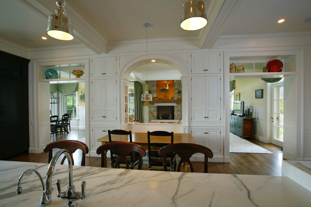 This is an example of a traditional eat-in kitchen in Philadelphia with an undermount sink, raised-panel cabinets, white cabinets and marble benchtops.