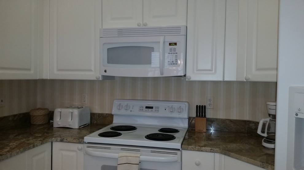 Small transitional u-shaped ceramic tile open concept kitchen photo in Miami with an undermount sink, raised-panel cabinets, white cabinets, granite countertops, multicolored backsplash, white appliances and a peninsula