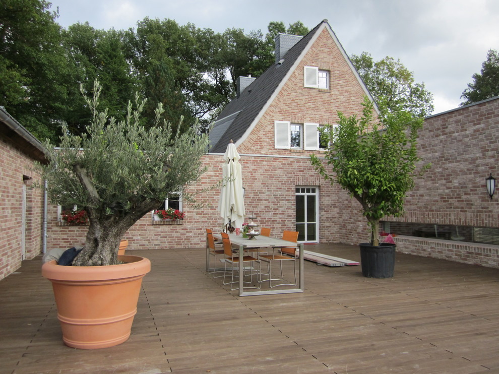 This is an example of an expansive country backyard deck in Dusseldorf with a container garden.