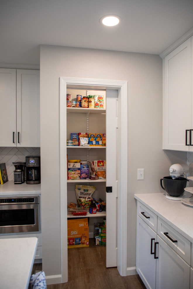 Example of a transitional vinyl floor kitchen design with shaker cabinets, white cabinets, quartz countertops, white backsplash, porcelain backsplash, stainless steel appliances and white countertops