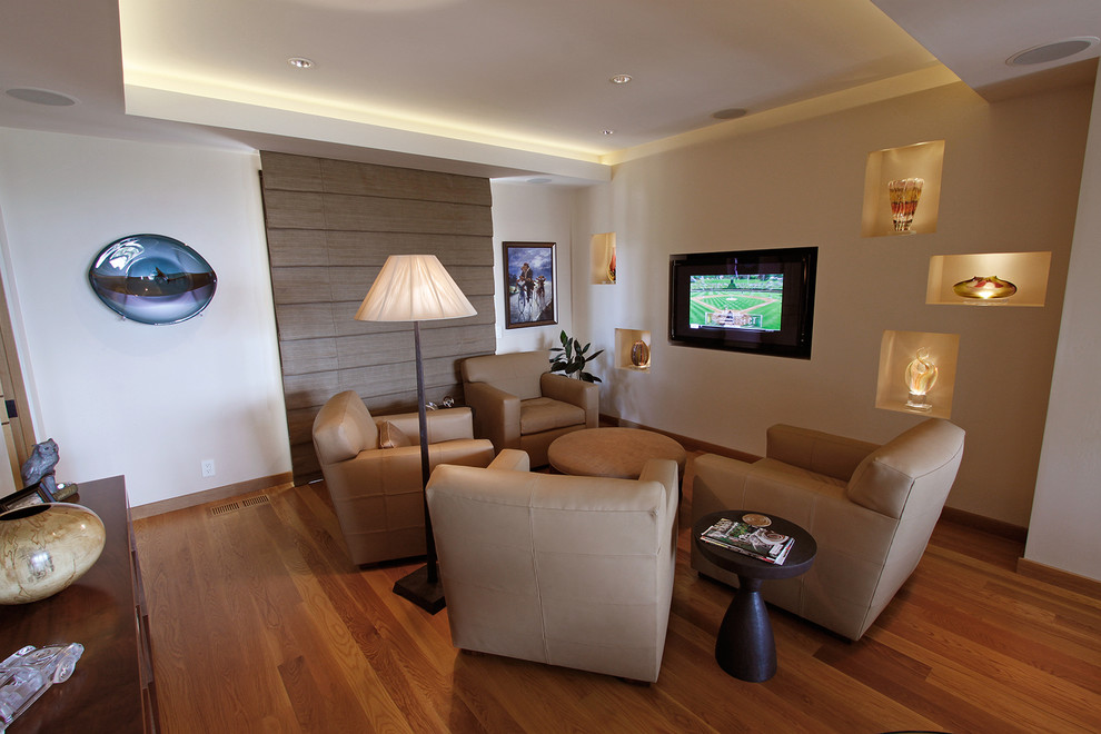 This is an example of a contemporary enclosed family room in San Diego with beige walls, medium hardwood floors and a wall-mounted tv.