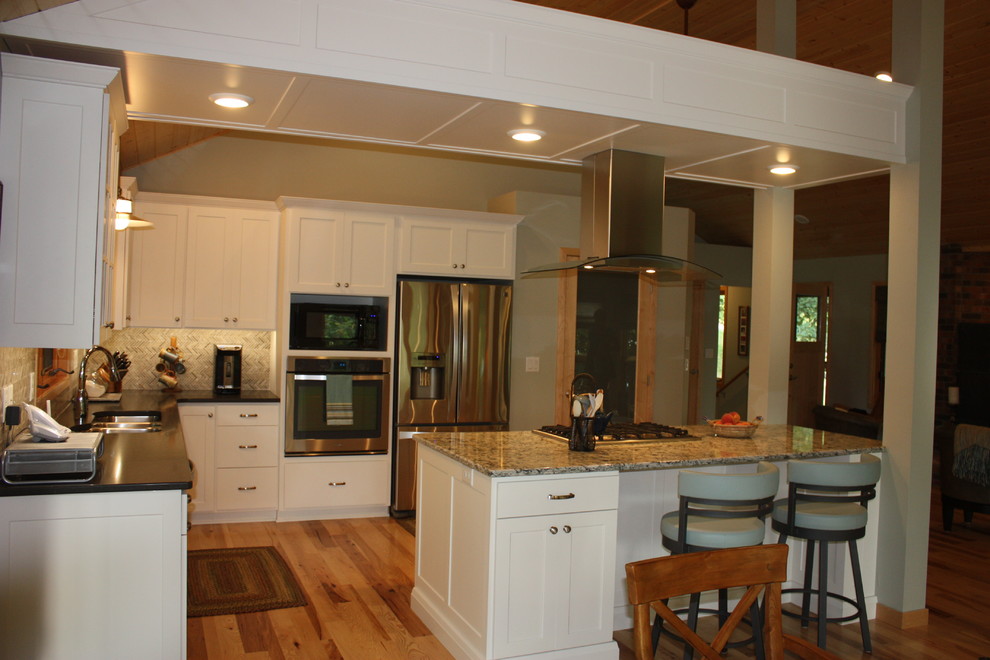 Inspiration for a large transitional l-shaped medium tone wood floor open concept kitchen remodel with a triple-bowl sink, recessed-panel cabinets, white cabinets, solid surface countertops, multicolored backsplash, mosaic tile backsplash, stainless steel appliances and an island
