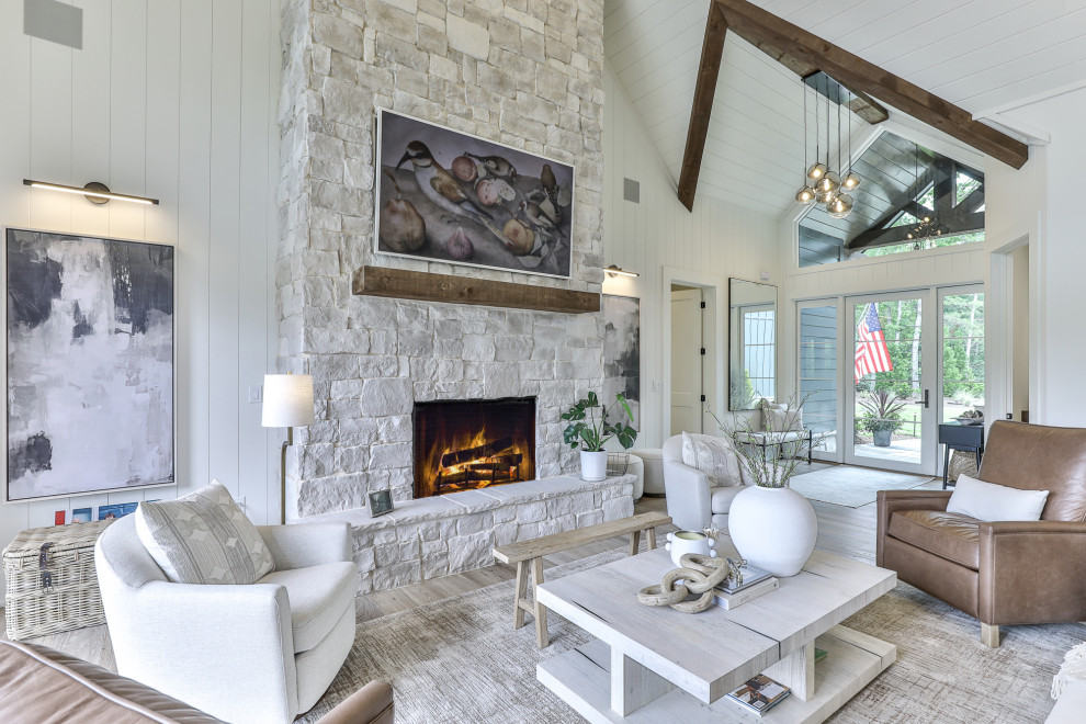 Example of a cottage open concept medium tone wood floor, brown floor, exposed beam, shiplap ceiling, vaulted ceiling and shiplap wall living room design with white walls, a standard fireplace, a stone fireplace and a wall-mounted tv
