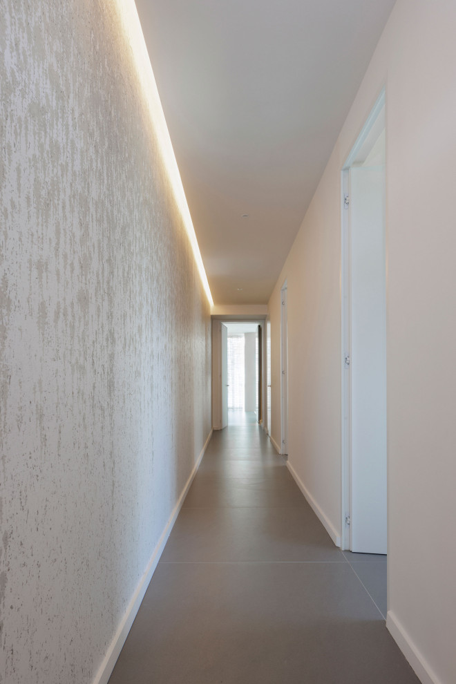 На фото: коридор среднего размера в стиле модернизм с белыми стенами, полом из керамогранита, серым полом, многоуровневым потолком и обоями на стенах с