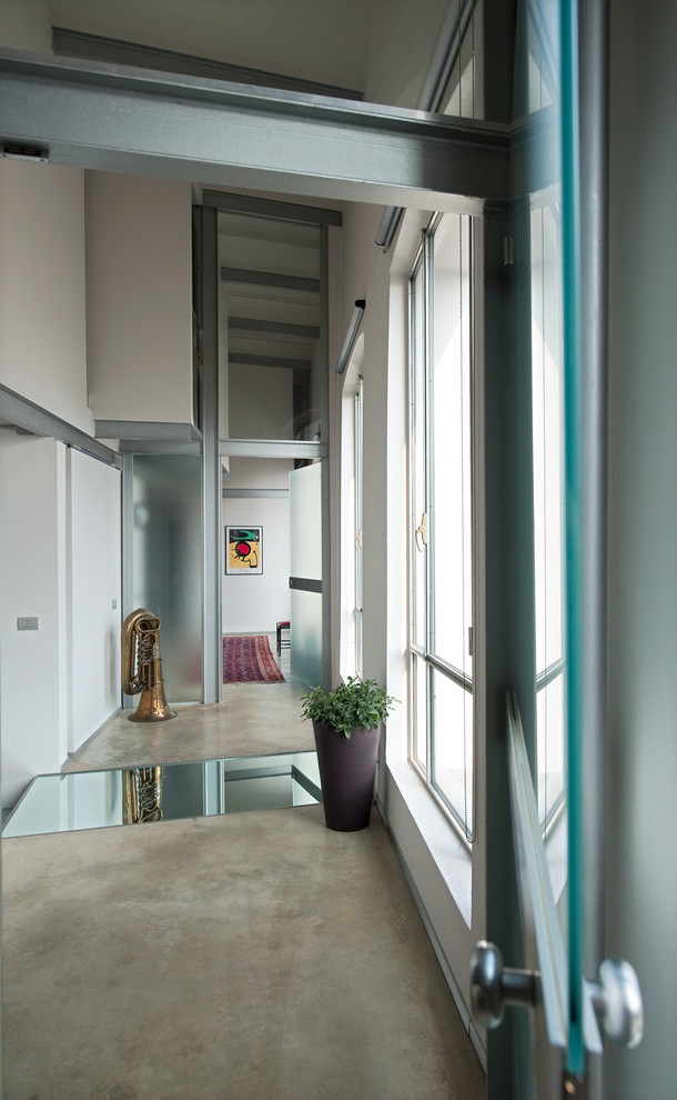 This is an example of a large industrial hallway in Milan with white walls, concrete floors and grey floor.