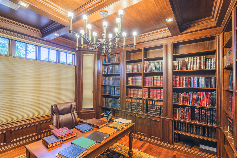 This is an example of a mid-sized traditional home office in New York with a library, brown walls, medium hardwood floors, a freestanding desk and brown floor.
