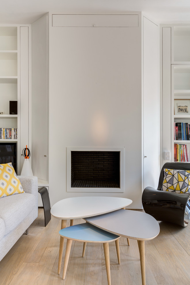 Photo of a large scandinavian open concept living room in Paris with a library, white walls, light hardwood floors, no fireplace, a freestanding tv and beige floor.