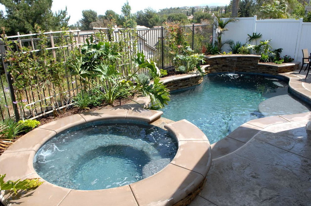 Inspiration for a mid-sized transitional backyard concrete paver and custom-shaped hot tub remodel in Orange County