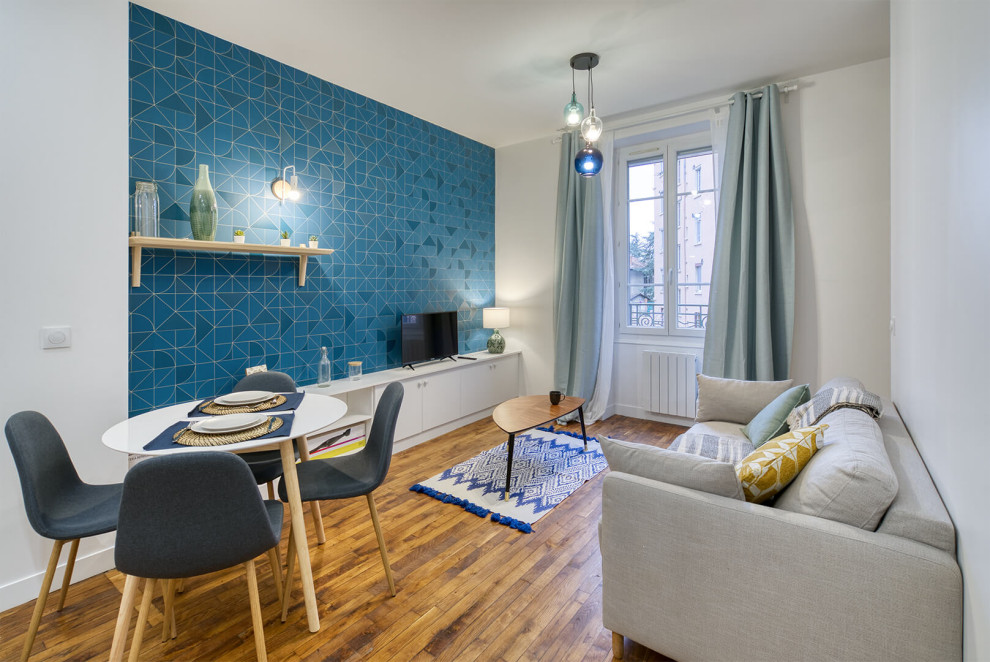 На фото: маленькая открытая гостиная комната в скандинавском стиле с с книжными шкафами и полками, синими стенами, темным паркетным полом, отдельно стоящим телевизором и обоями на стенах для на участке и в саду