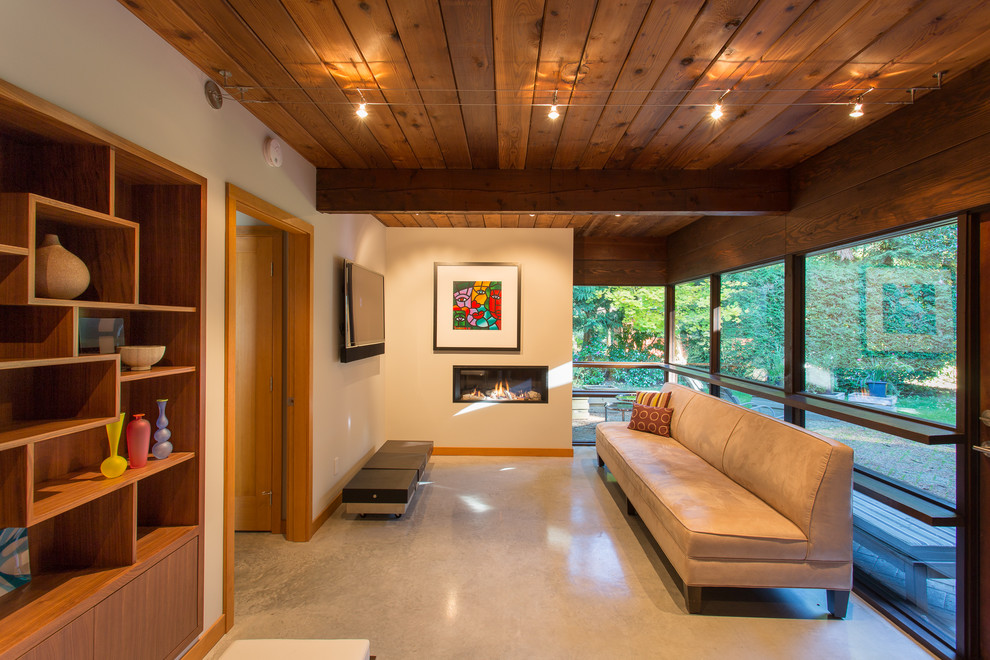 This is an example of a mid-sized midcentury open concept family room in Vancouver with beige walls, concrete floors, a ribbon fireplace, a plaster fireplace surround, a wall-mounted tv and grey floor.