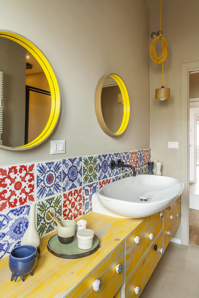 Inspiration for a mid-sized mediterranean 3/4 bathroom in Florence with shaker cabinets, yellow cabinets, an alcove shower, a two-piece toilet, multi-coloured tile, ceramic tile, beige walls, concrete floors, a vessel sink, wood benchtops, beige floor, a hinged shower door, yellow benchtops, a shower seat, a single vanity and a floating vanity.