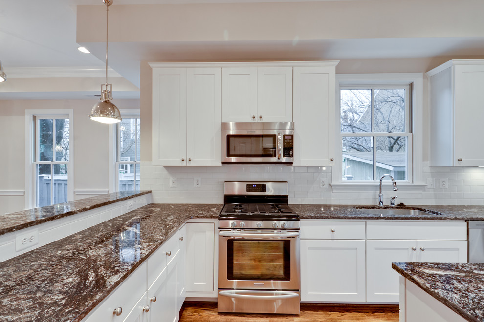 Inspiration for an u-shaped medium tone wood floor open concept kitchen remodel in DC Metro with an undermount sink, shaker cabinets, white cabinets, granite countertops, white backsplash, subway tile backsplash and stainless steel appliances