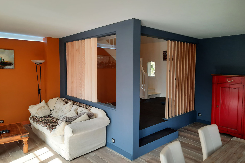 Idée de décoration pour une grande salle de séjour design avec un mur orange, un sol en carrelage de céramique et un sol marron.