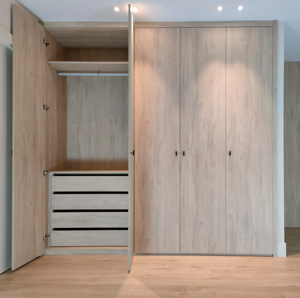 Foto de armario y vestidor minimalista grande con a medida, armarios con paneles empotrados, puertas de armario de madera clara y suelo de madera clara