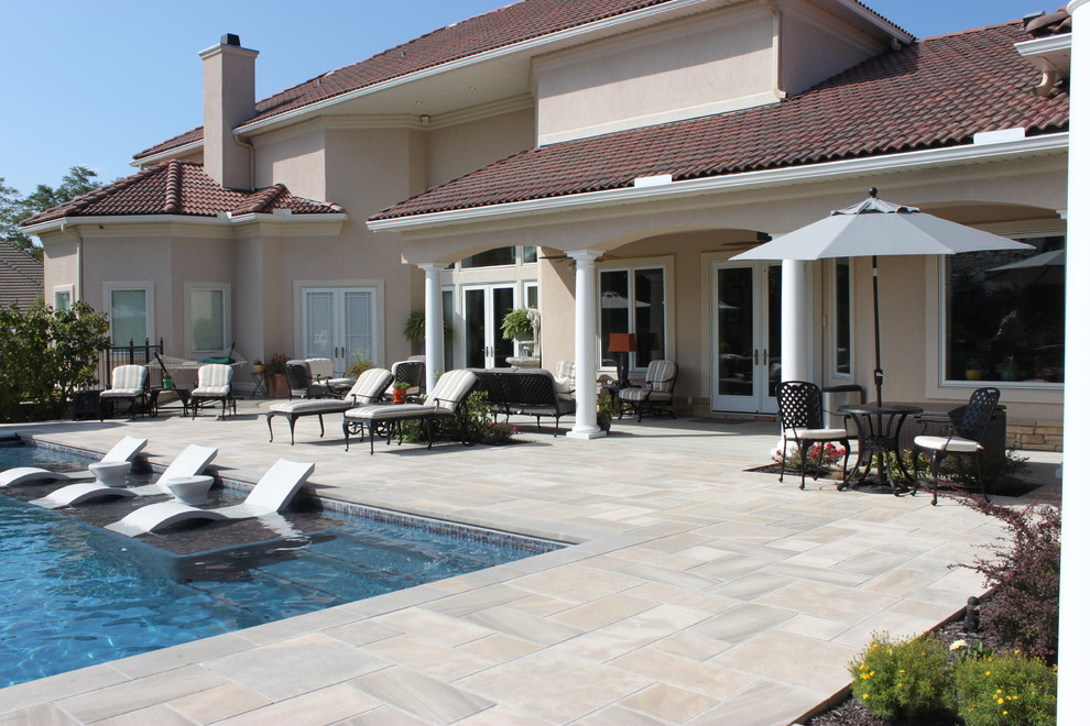Inspiration for a large mediterranean backyard rectangular pool in Kansas City with a water feature and natural stone pavers.