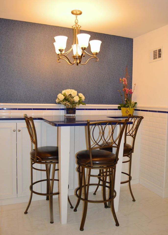 Example of a large u-shaped porcelain tile eat-in kitchen design in Boston with white cabinets, white backsplash, stainless steel appliances, an island, a single-bowl sink, recessed-panel cabinets, glass countertops and ceramic backsplash