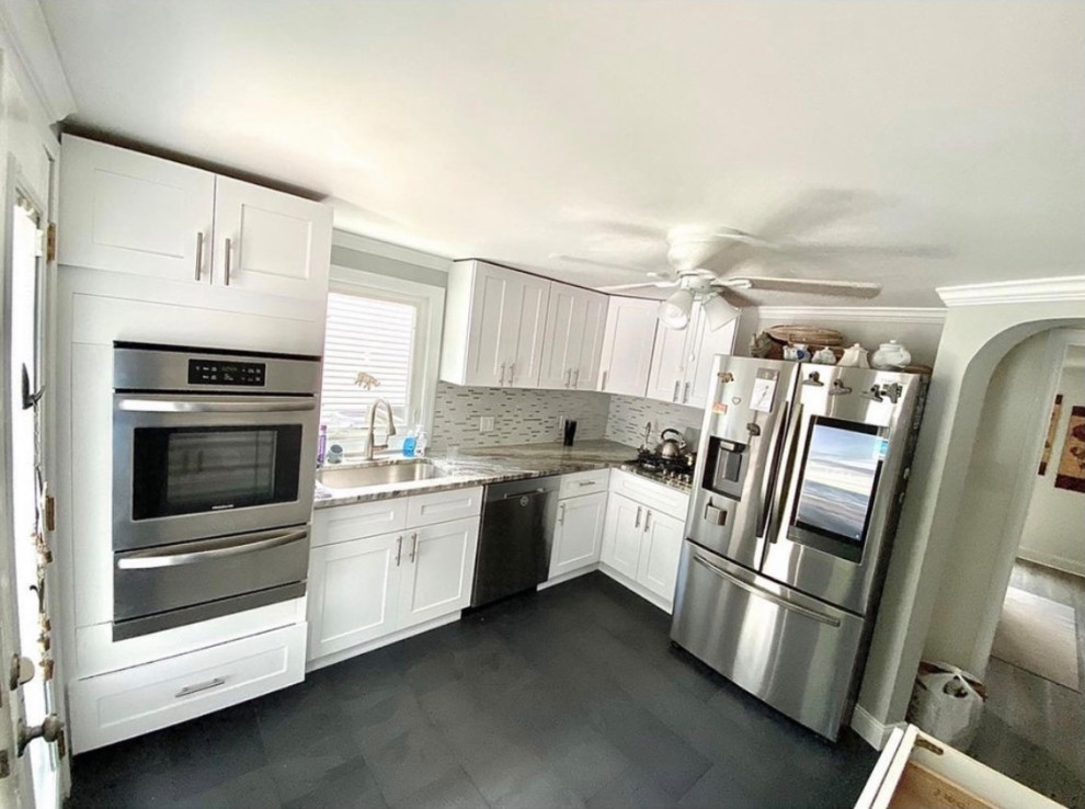 This is an example of a small modern l-shaped separate kitchen in Philadelphia with an undermount sink, shaker cabinets, white cabinets, granite benchtops, white splashback, glass tile splashback, stainless steel appliances, slate floors, no island, black floor and grey benchtop.