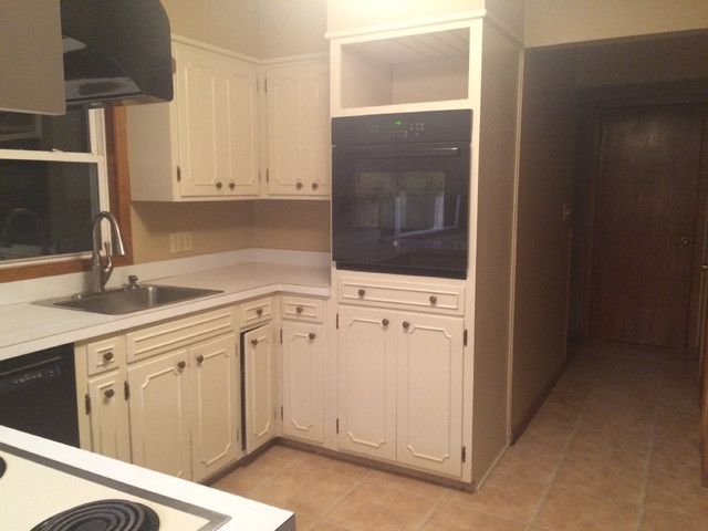 Example of a mid-sized transitional u-shaped medium tone wood floor eat-in kitchen design in Other with a double-bowl sink, raised-panel cabinets, dark wood cabinets, quartz countertops, beige backsplash, glass tile backsplash, black appliances and a peninsula