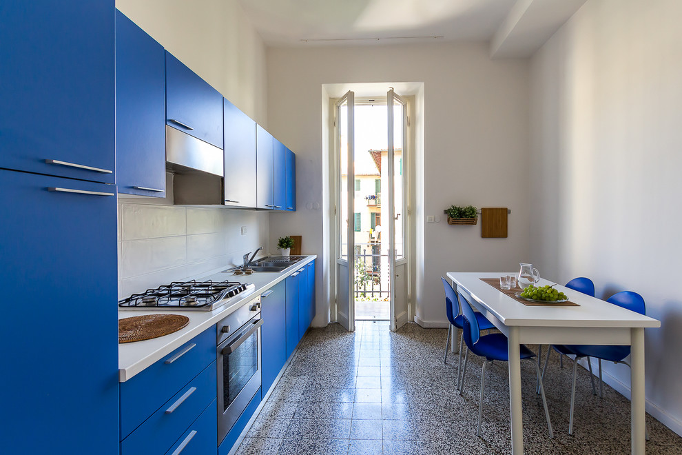 This is an example of a mid-sized contemporary single-wall eat-in kitchen in Florence with a double-bowl sink, flat-panel cabinets, blue cabinets, white splashback, stainless steel appliances, no island, ceramic splashback, ceramic floors and multi-coloured floor.