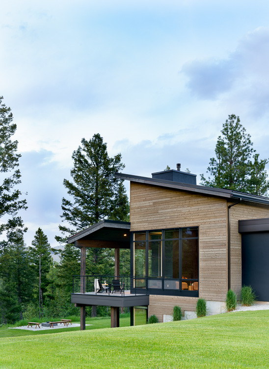 Cette photo montre une grande façade de maison marron tendance en bois et bardage à clin à un étage avec un toit en appentis, un toit en métal et un toit noir.