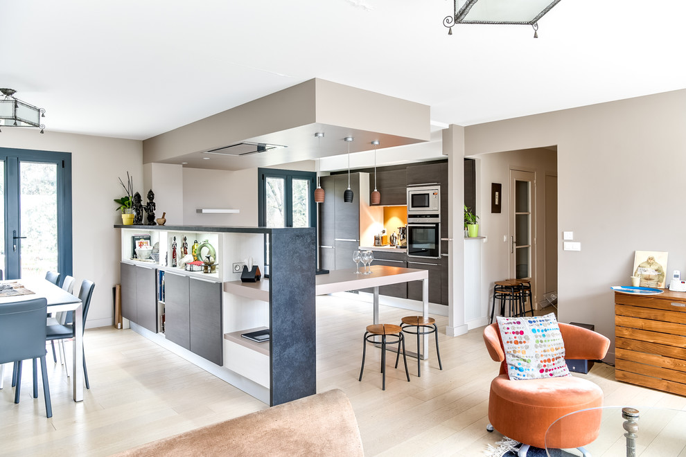Photo of a large modern l-shaped eat-in kitchen in Lyon with an undermount sink, flat-panel cabinets, medium wood cabinets, granite benchtops, orange splashback, stainless steel appliances, light hardwood floors, a peninsula, timber splashback, beige floor and grey benchtop.