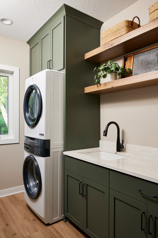 Example of a small transitional single-wall utility room design in Minneapolis with an undermount sink, shaker cabinets, green cabinets, quartz countertops, a stacked washer/dryer and beige countertops