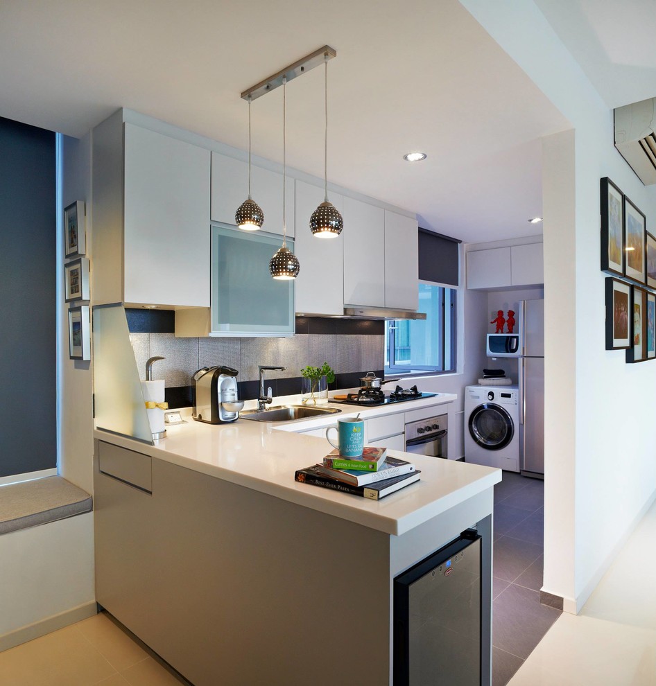 Design ideas for a small contemporary l-shaped open plan kitchen in Singapore with a single-bowl sink, flat-panel cabinets, grey cabinets, solid surface benchtops, metallic splashback, porcelain splashback, stainless steel appliances, porcelain floors and a peninsula.