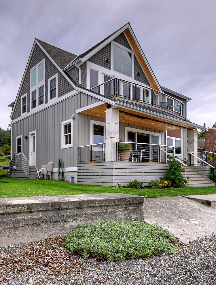 Mid-sized beach style two-storey grey house exterior in Seattle with a gable roof, a shingle roof, a grey roof and board and batten siding.