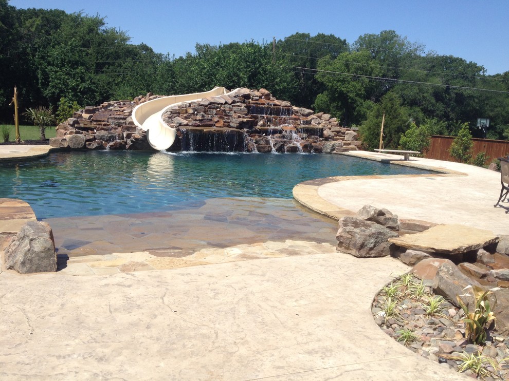 This is an example of an expansive beach style backyard custom-shaped lap pool in Dallas with stamped concrete and a water slide.