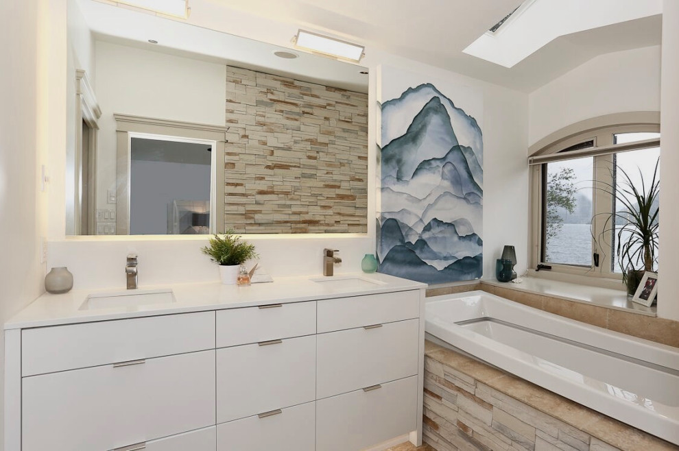 Photo of a mid-sized beach style 3/4 bathroom in Vancouver with flat-panel cabinets, white cabinets, a corner tub, slate, white walls, limestone floors, an undermount sink, engineered quartz benchtops, beige floor and white benchtops.
